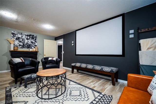 cinema room with light wood finished floors, baseboards, and a textured ceiling