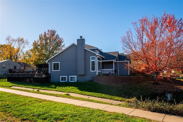 view of side of home with a lawn and a chimney