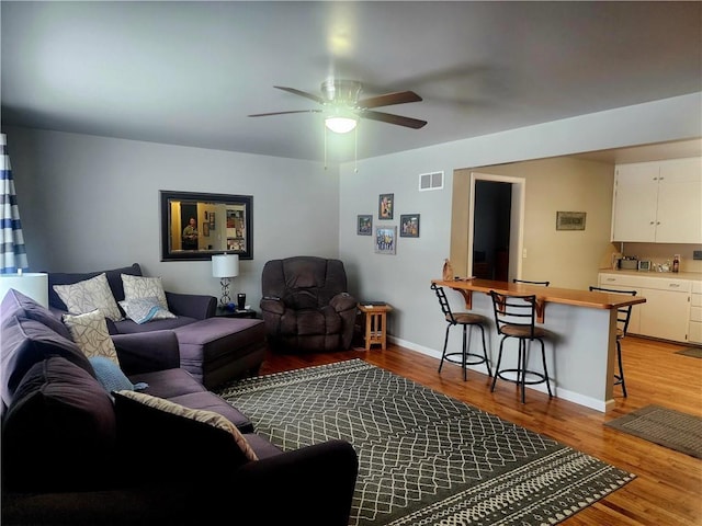 living area with visible vents, ceiling fan, light wood-style flooring, and baseboards