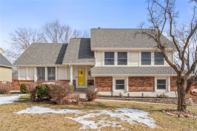 split level home featuring roof with shingles and brick siding