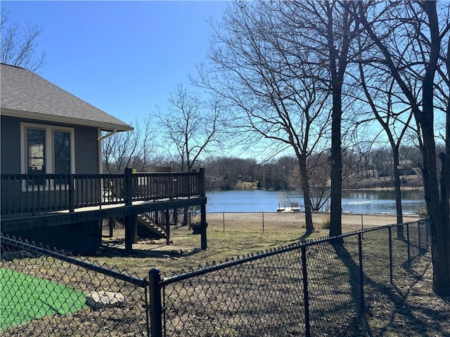 view of yard featuring stairway, a deck with water view, and fence