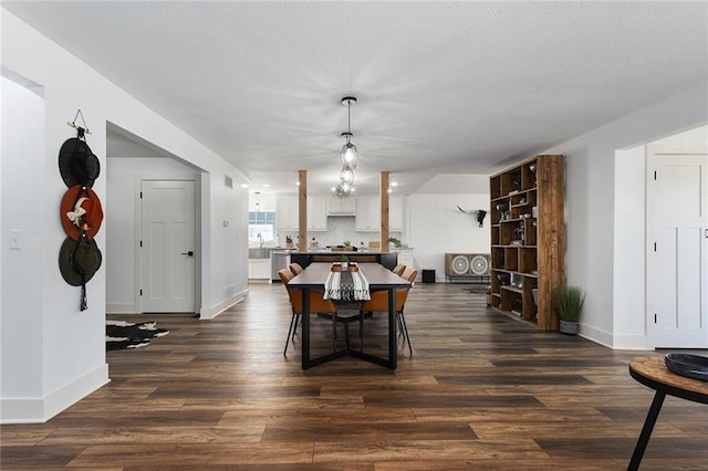 dining area with a textured ceiling, baseboards, and dark wood-style flooring