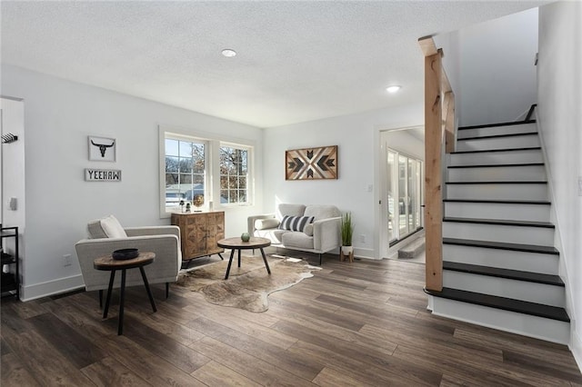 living area with a textured ceiling, stairway, wood finished floors, and baseboards