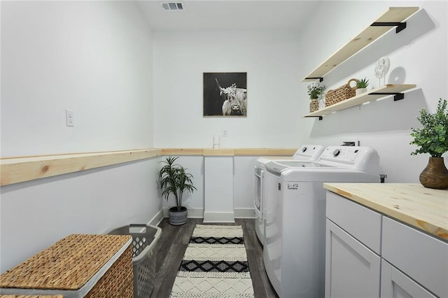 clothes washing area with cabinet space, baseboards, visible vents, dark wood-style floors, and washer and dryer