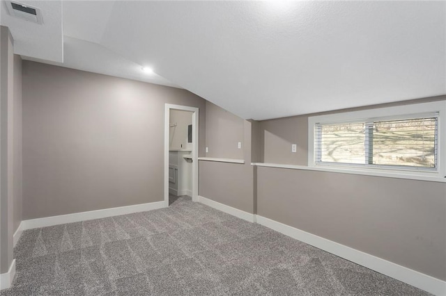 empty room featuring carpet, visible vents, baseboards, and vaulted ceiling