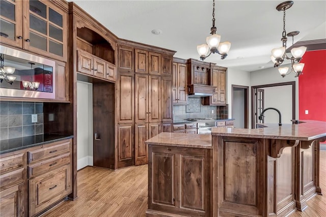 kitchen with stainless steel appliances, decorative light fixtures, and light wood finished floors