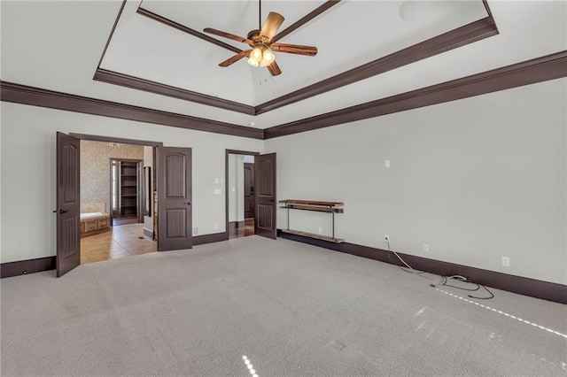 empty room featuring carpet, a tray ceiling, ornamental molding, a ceiling fan, and baseboards