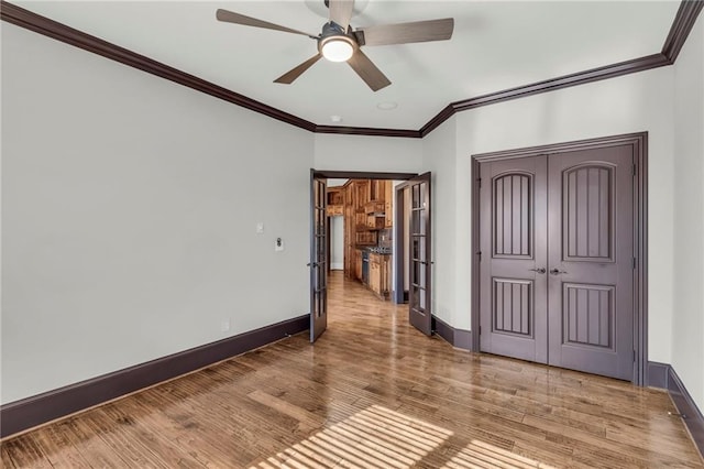 spare room featuring a ceiling fan, crown molding, baseboards, and wood finished floors