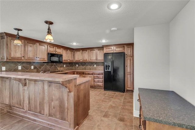 kitchen featuring pendant lighting, decorative backsplash, black appliances, a peninsula, and a kitchen bar