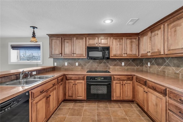 kitchen with black appliances, a sink, visible vents, and brown cabinets