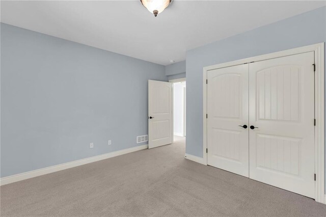 unfurnished bedroom featuring carpet, a closet, visible vents, and baseboards