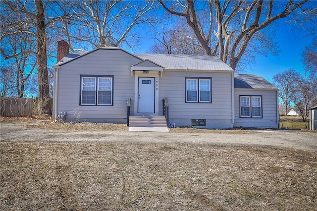 bungalow-style house with a chimney and fence