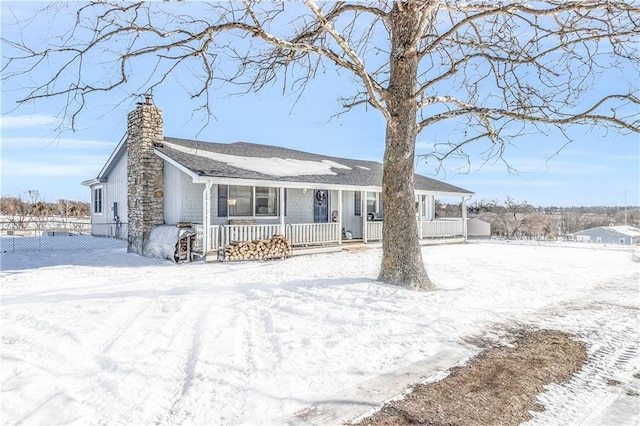 view of front of home featuring covered porch, a chimney, and fence