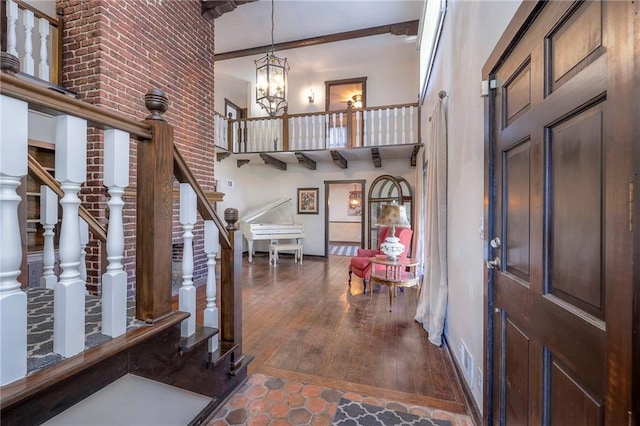 foyer entrance featuring stairs, a high ceiling, a notable chandelier, and wood finished floors