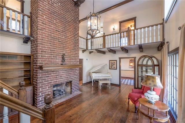 living room with a high ceiling, wood-type flooring, a fireplace, and an inviting chandelier