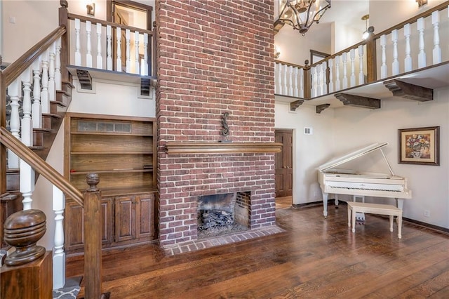 living area with a high ceiling, baseboards, a fireplace, and wood finished floors