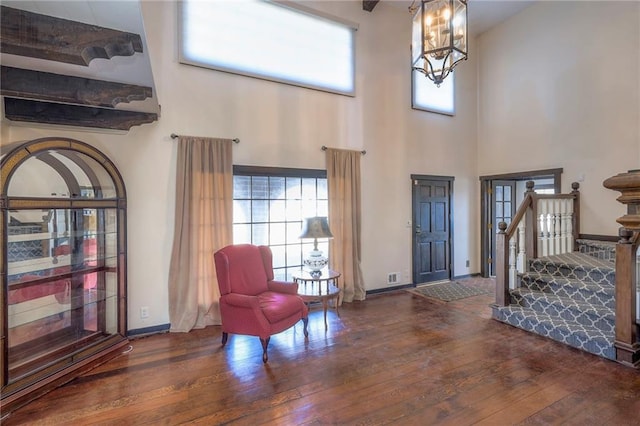 foyer entrance with a towering ceiling, hardwood / wood-style floors, a chandelier, baseboards, and stairs