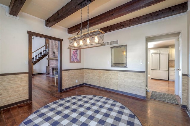 dining room featuring hardwood / wood-style floors, beamed ceiling, wainscoting, and visible vents