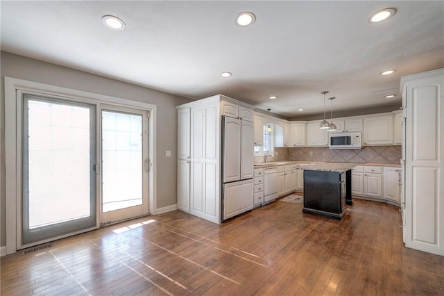 kitchen featuring white appliances, decorative backsplash, light countertops, and dark wood-type flooring