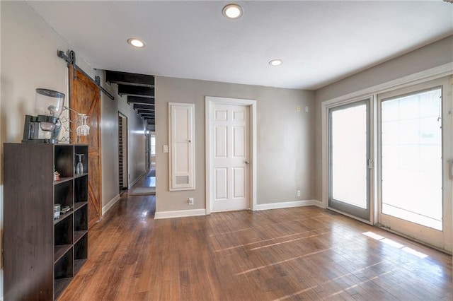 unfurnished room with recessed lighting, a barn door, baseboards, and wood finished floors