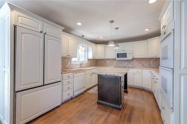 kitchen featuring wood finished floors, white appliances, light countertops, and white cabinetry