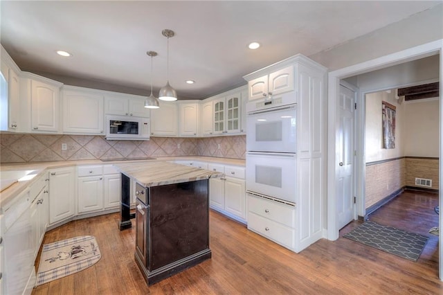 kitchen featuring white appliances, visible vents, wood finished floors, light countertops, and white cabinetry