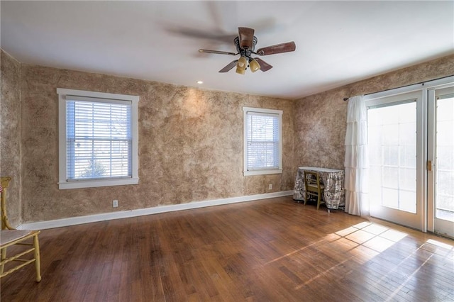 interior space featuring a ceiling fan, baseboards, and hardwood / wood-style floors