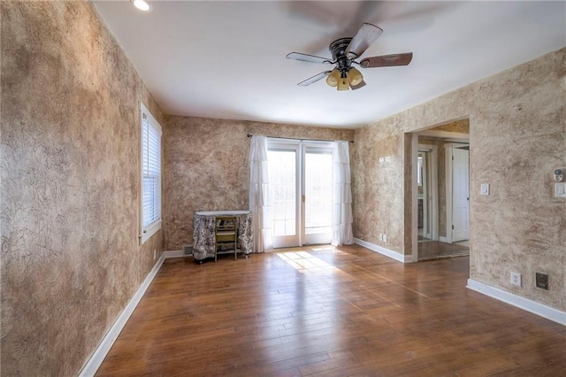 unfurnished living room featuring a healthy amount of sunlight, ceiling fan, baseboards, and hardwood / wood-style flooring