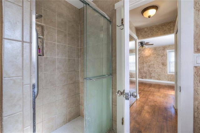 bathroom with a ceiling fan, a stall shower, baseboards, and wood finished floors