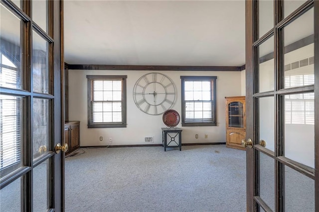 unfurnished room with a healthy amount of sunlight, baseboards, carpet flooring, and french doors