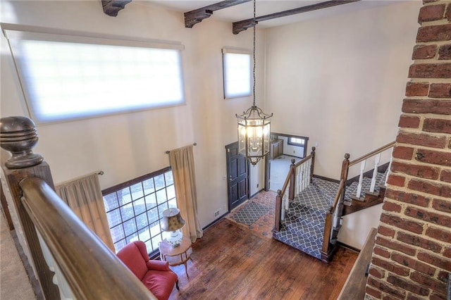 foyer entrance with stairs, wood-type flooring, and beam ceiling