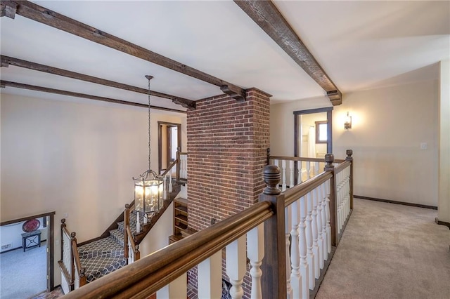 hall featuring beamed ceiling, carpet flooring, an upstairs landing, and baseboards