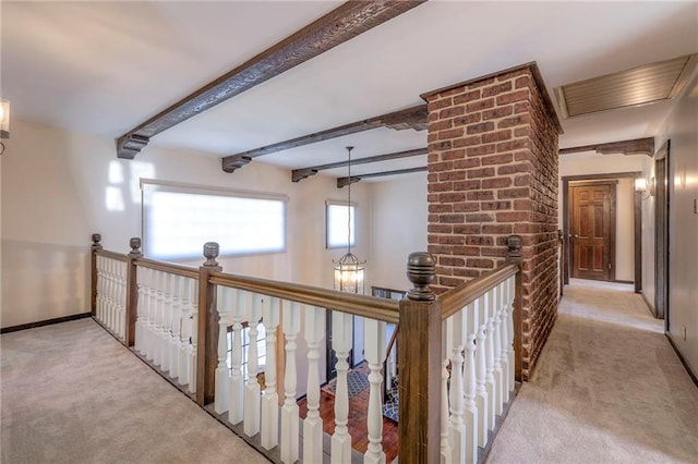 corridor with light carpet, an upstairs landing, beam ceiling, and baseboards