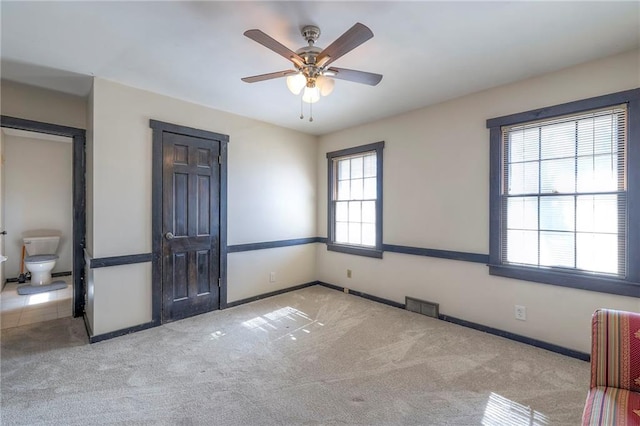 spare room featuring a ceiling fan, carpet flooring, visible vents, and baseboards