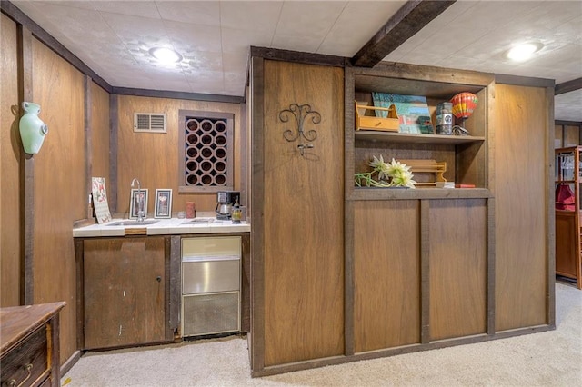 bar featuring visible vents, light colored carpet, wet bar, wood walls, and a sink