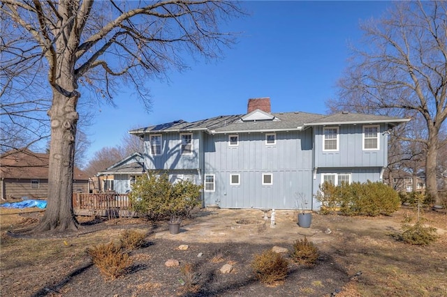 rear view of property featuring a chimney and a wooden deck