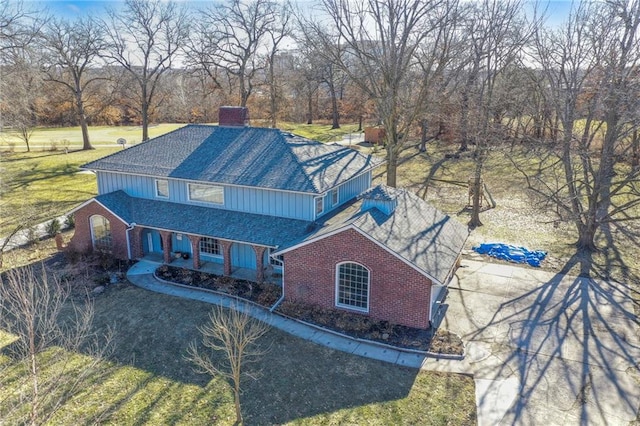 view of front facade with driveway, brick siding, and a shingled roof