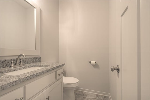 bathroom with baseboards, vanity, and toilet