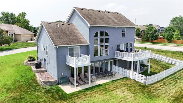 back of property with a shingled roof, a patio area, a yard, and stucco siding