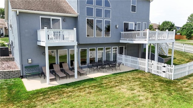 rear view of property with a yard, stucco siding, a shingled roof, a patio area, and fence