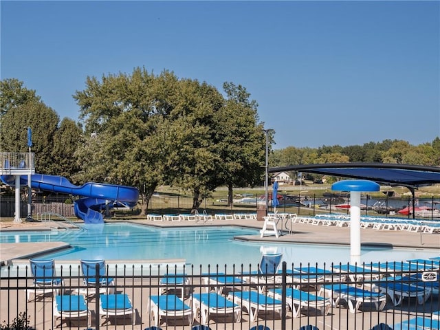 pool featuring a water slide, fence, and a patio