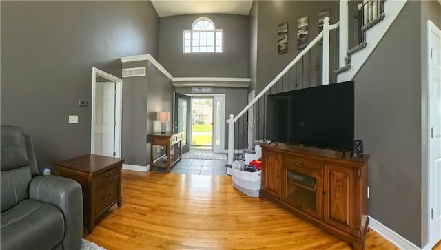 living room featuring light wood-type flooring, a healthy amount of sunlight, visible vents, and stairs