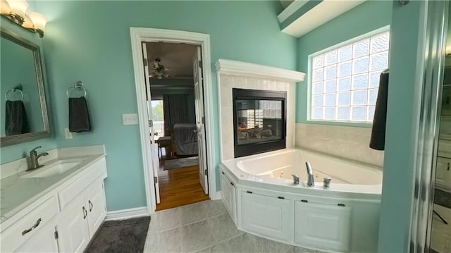 bathroom featuring baseboards, tile patterned floors, vanity, a fireplace, and a bath