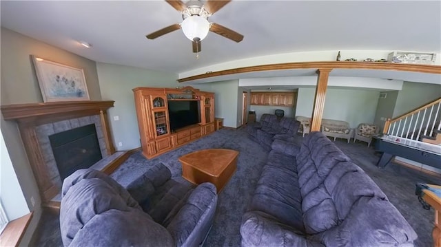 carpeted living room featuring ceiling fan, stairway, and a tiled fireplace