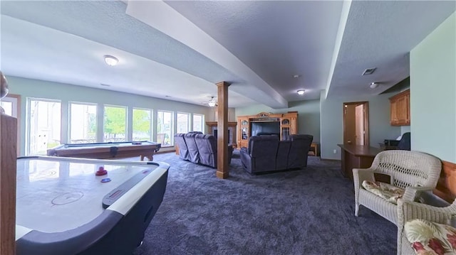 game room featuring visible vents, dark carpet, a ceiling fan, a textured ceiling, and ornate columns