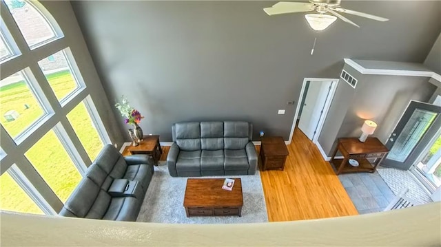 living room with a towering ceiling, baseboards, and a ceiling fan