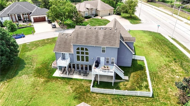 rear view of house with a patio, a garage, a shingled roof, a lawn, and stucco siding