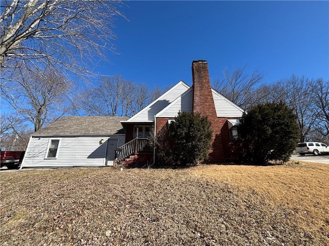 view of side of property featuring a chimney and brick siding