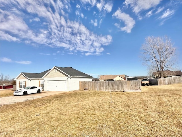 exterior space featuring a garage, driveway, fence, and a front lawn