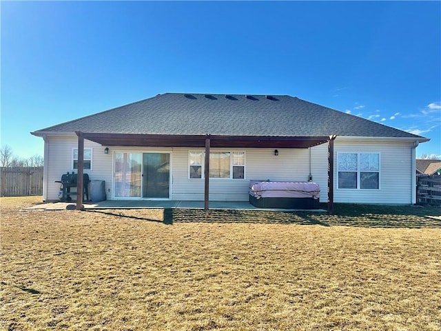 rear view of house with roof with shingles, a lawn, a patio area, and fence